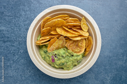 Top view of a portion of fried plantain chips with guacamole.