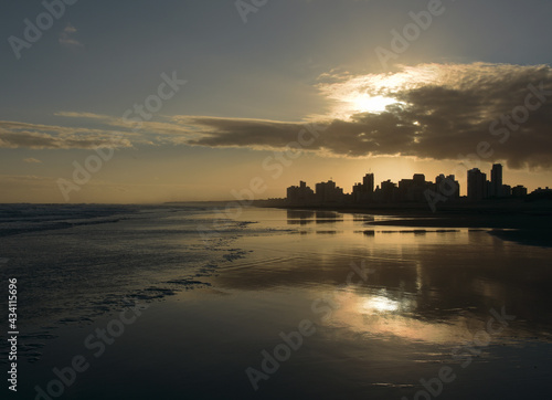 Beautiful postcard of a sunset with light on the beach with the city in the background