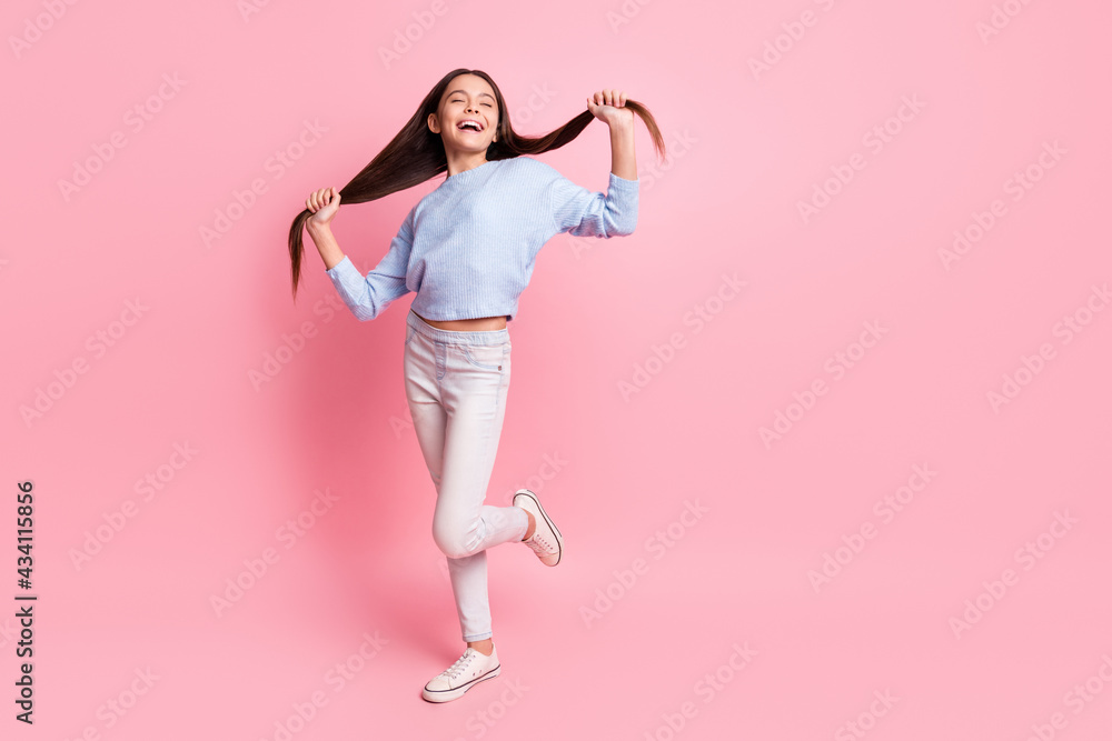 Full length body size view of attractive dreamy cheerful girl having fun making tails isolated over pink pastel color background Full length body size view of attractive dreamy cheerful girl having fun making tails isolated over pink pastel color background
