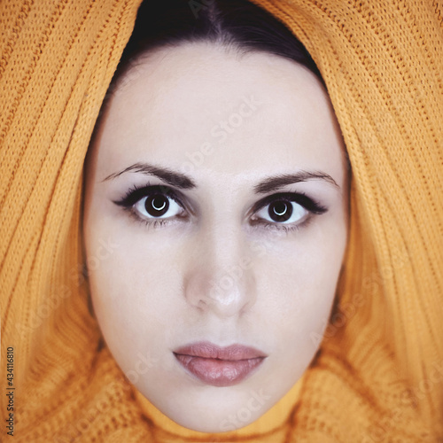 Close-up portrait of a beautiful young woman posing in bright yellow knitted sweater. Knitwear fashion.