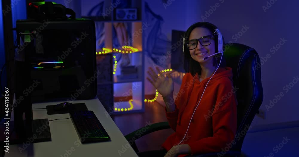 Portrait, a beautiful woman streamer sits in a computer chair and waves her hand, greets the participants of the stream. Young woman streamer smiling, she is happy, online conference. 4k, ProRes Portrait, a beautiful woman streamer sits in a computer chair and waves her hand, greets the participants of the stream. Young woman streamer smiling, she is happy, online conference. 4k, ProRes