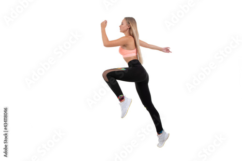A sporty young woman in a pink top, leggings and sneakers does exercises on a white background