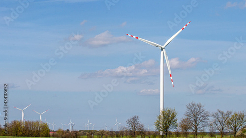 wind turbine in the wind against the backdrop of blue sky with clouds