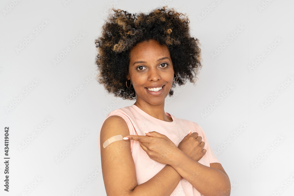 Young african american woman showing her arm with band aid after coronavirus Covid-19 vaccine injection. Covid vaccination concept Young african american woman showing her arm with band aid after coronavirus Covid-19 vaccine injection. Covid vaccination concept