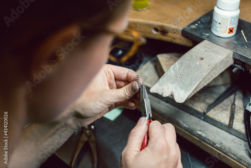 Diligent jeweler working on a chain cutting off some links © Kzenon