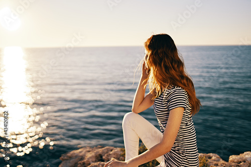 woman sitting on the beach near the sea in the mountains and watching the sunset