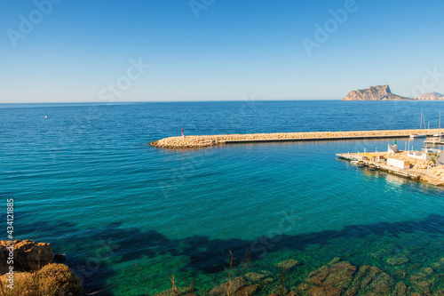 Maritime landscape with a breakwater with a small red lighthouse, in Moraira, Alicante (Spain)