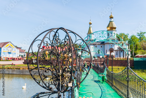 Bridge with padlocks over the river with a church on the background