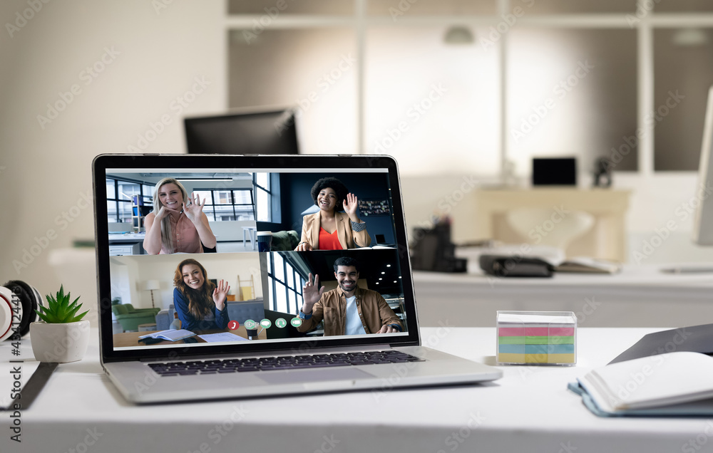 Diverse group of people having business video call on screen of laptop on desk Diverse group of people having business video call on screen of laptop on desk