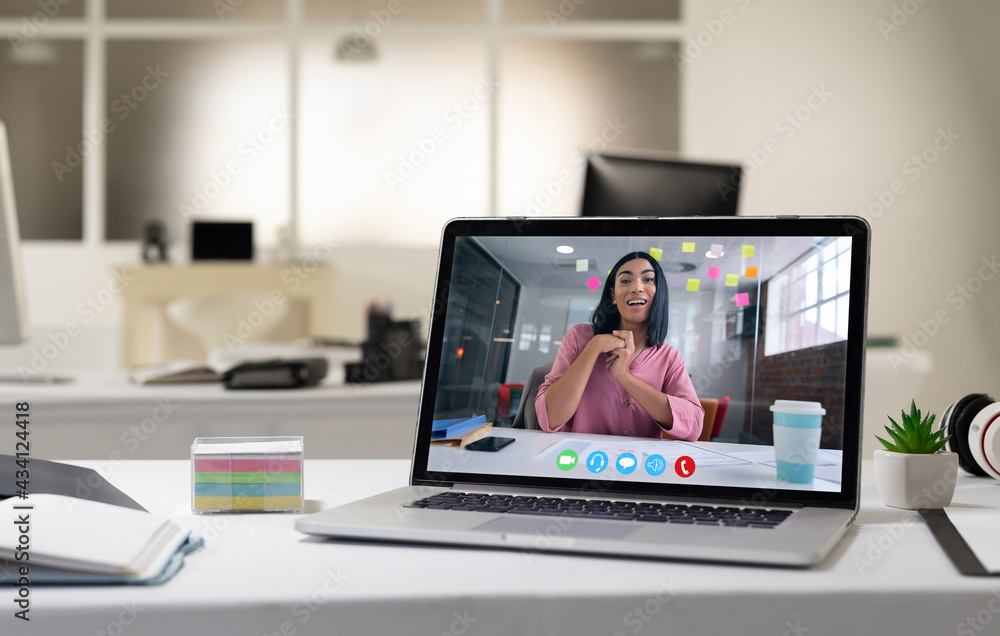 Mixed race woman having business video call on screen of laptop on desk Mixed race woman having business video call on screen of laptop on desk