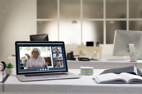 Diverse group of people having business video call on screen of laptop on desk