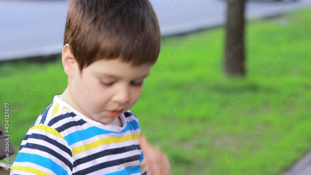 A small child eats French fries on a city street, sitting on a bench. Fast food for kids A small child eats French fries on a city street, sitting on a bench. Fast food for kids