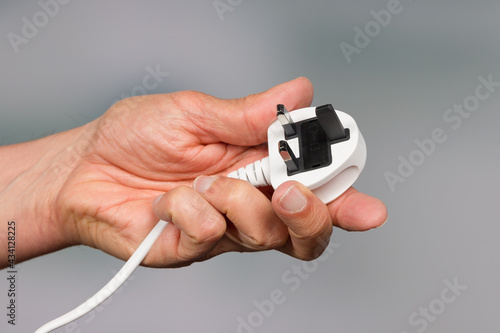 a hand is holding a three pin power plug