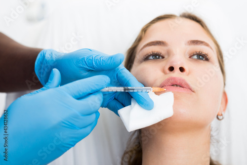 Young woman getting procedure of injection contouring and lip augmentation for facial correction in cosmetology clinic