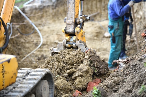 Obraz na płótnie A combination of heavy excavator equipment and human masonry work in building a house w salonie