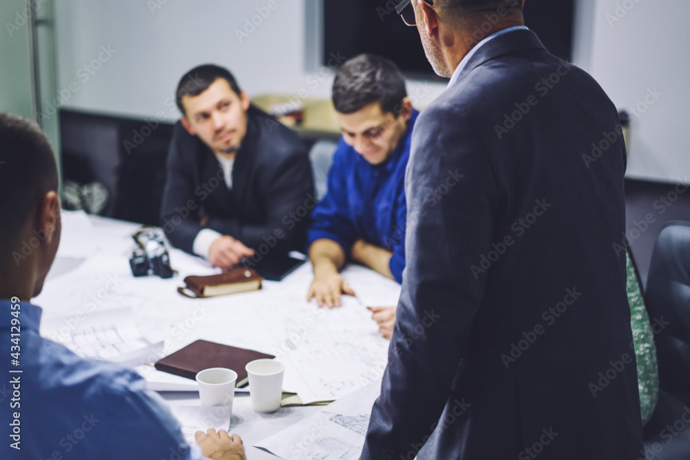 Obraz premium Crew of professional architects have productive collaboration completing sketch for project together, experienced designers developing paper blueprint checking details during briefing teamwork