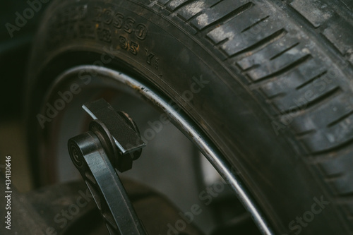 Closeup of a car tire with numbers on it missing its rim in a workshop