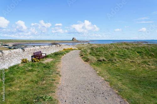 Footpath beside a stone wall leading to a distant Lindisfarne Castle © Steven Bramall