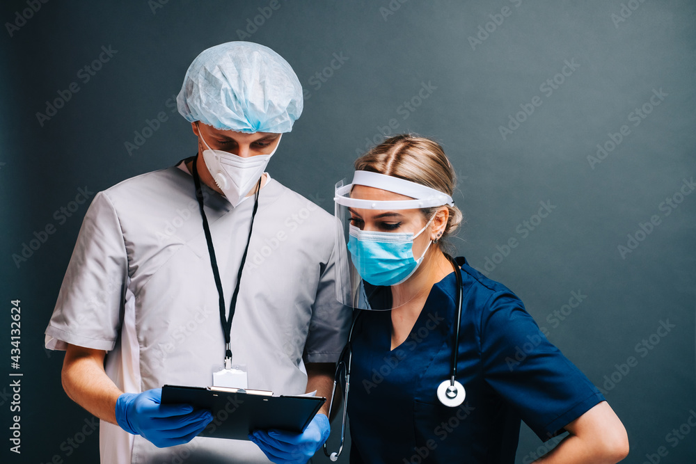 Portrait of hospital workers nurses colleagues in medical protective masks isolated on dark background. Portrait of hospital workers nurses colleagues in medical protective masks isolated on dark background.