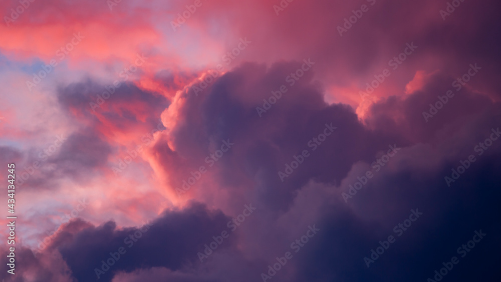 Magenta and blue contrasting intense vibrant dramatic cloudscape scenery with clouds lit up in various shades against blazing sunset. Climate and weather condition backdrop concept. Wallpaper.