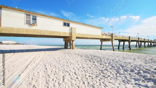 Panning wide angle view shot of Okaloosa island fishing pier in Fort Walton Beach, Florida with green waves in Panhandle Gulf of Mexico on sunny sun day photo