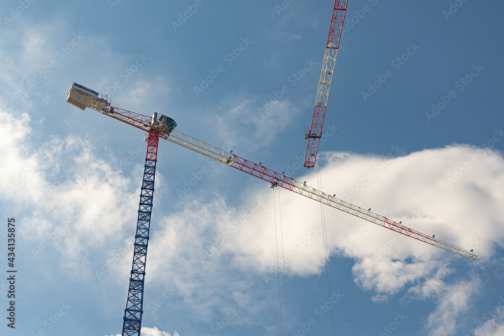 Steel isolated cranes in a building construction site to build skyscraper. Blue sky on the background.