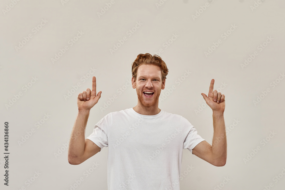 Young redhead attractive man looks very happy and points with fingers up Young redhead attractive man looks very happy and points with fingers up