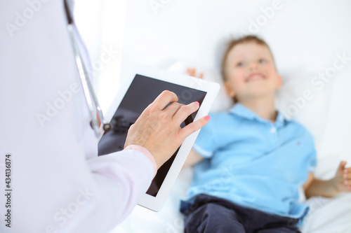 Happy smiling male kid-patient at usual medical inspection. Doctor and young boy in the clinic. Medicine concepts © volha_r