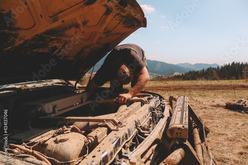 Repair of off-road cars in the mountains. breakage. The repairman repairs the engine. photo