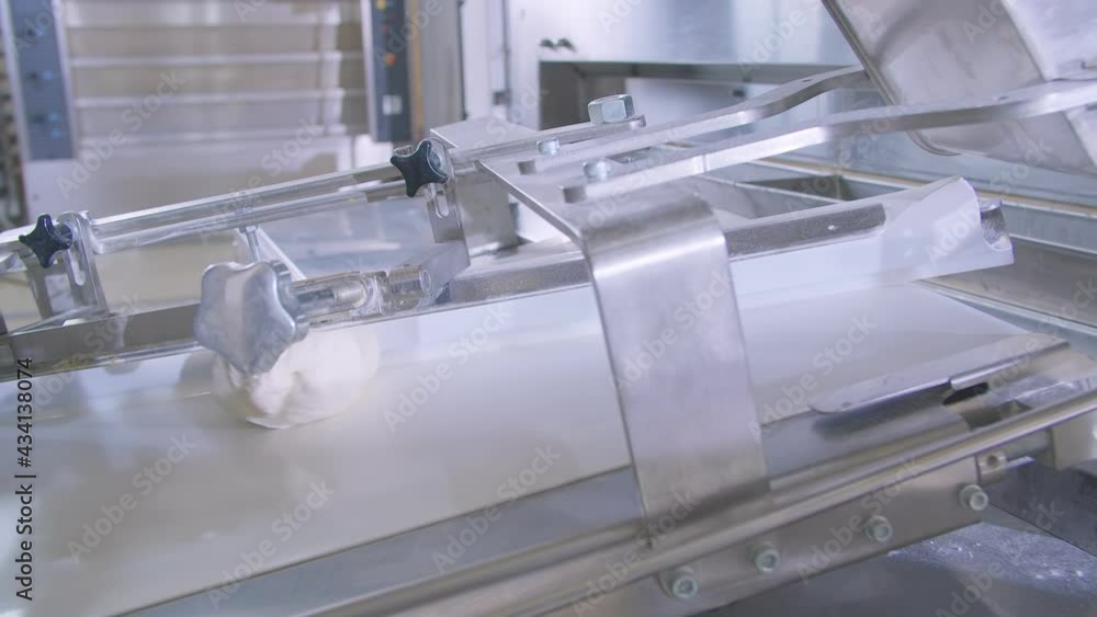 Dough pieces on the working conveyor line of dough machine in a bakery. Slow motion Dough pieces on the working conveyor line of dough machine in a bakery. Slow motion