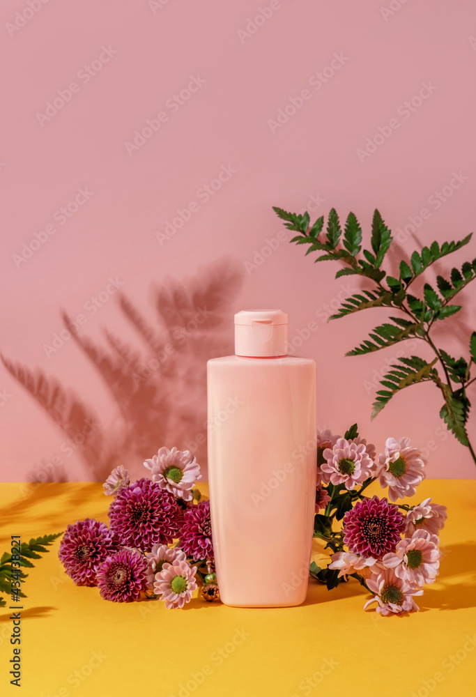Summer style of showcase for cosmetics product display on yellow and pink background with flowers. Pink bottle cosmetics product with flowers Summer style of showcase for cosmetics product display on yellow and pink background with flowers. Pink bottle cosmetics product with flowers