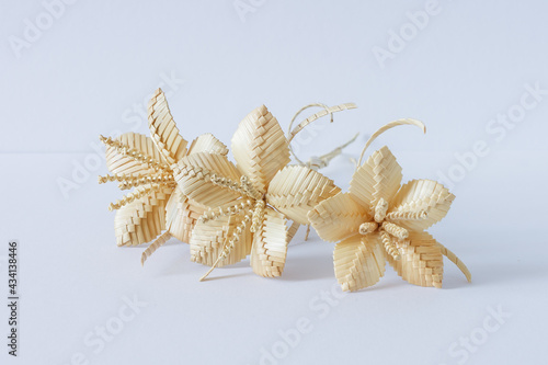 Three flowers are made of straw on a white background © Roman
