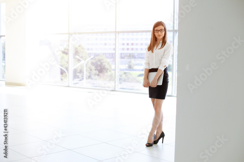 Free Download Beautiful female specialist with copy space area standing in sunny office and smiling charmingly. Business people concept - GFXLoad