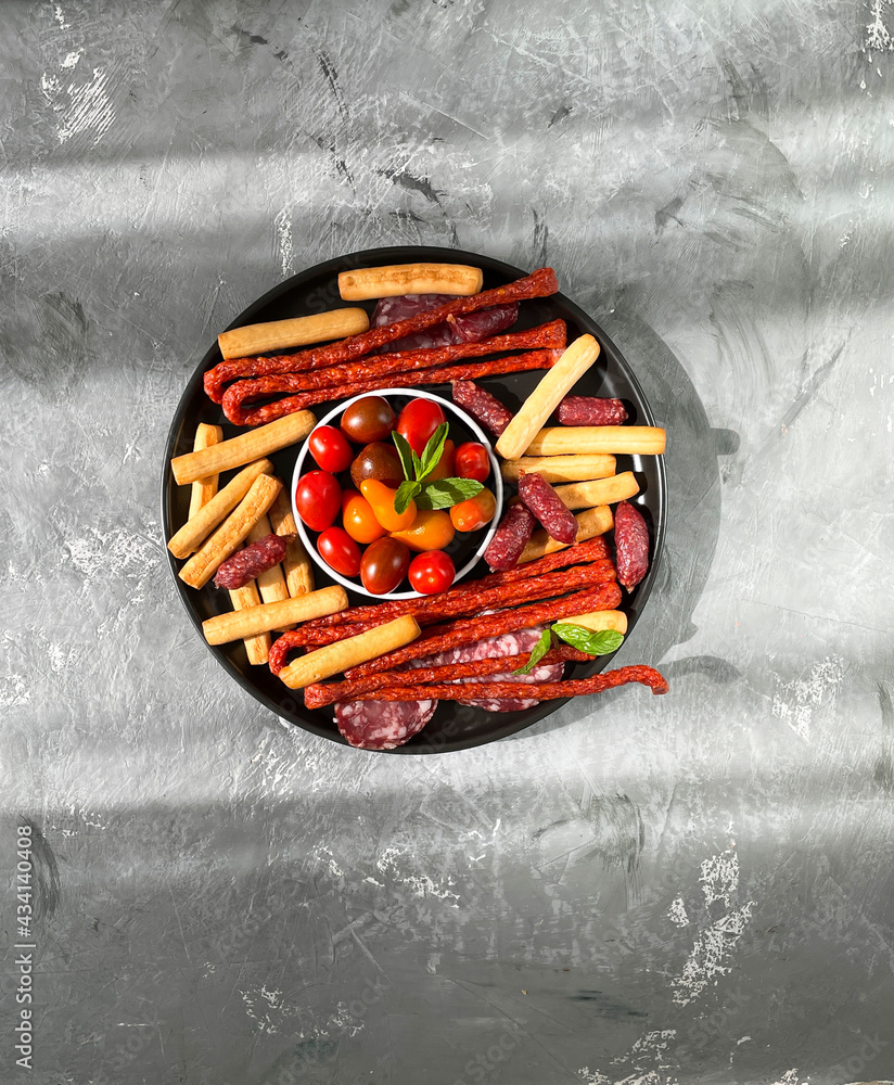 Antipasto delicacy-smoked salami sausages, breadsticks, cherry. Top view with copy space.