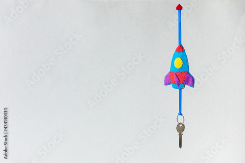 Flying up felt rocket toy with a key on a string on a grey background. The creative concept of children's education, opening up new horizons. Copy space