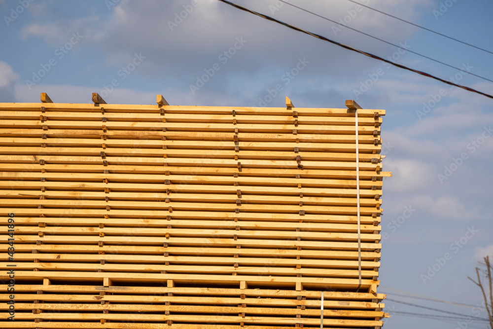 Storage of piles of wooden boards on the sawmill. Boards are stacked in a carpentry shop. Sawing drying and marketing of wood. Pine lumber for furniture production, construction. Lumber Industry. Storage of piles of wooden boards on the sawmill. Boards are stacked in a carpentry shop. Sawing drying and marketing of wood. Pine lumber for furniture production, construction. Lumber Industry.