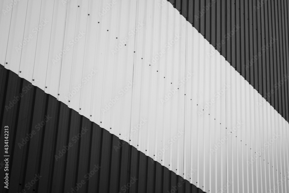 Black and white corrugated iron sheet used as a facade of a warehouse or factory. Texture of a seamless corrugated zinc sheet metal aluminum facade. Architecture. Metal texture. Black and white corrugated iron sheet used as a facade of a warehouse or factory. Texture of a seamless corrugated zinc sheet metal aluminum facade. Architecture. Metal texture.