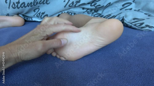 4K Viewing hand of adult tickling sole of child in bed
 photo