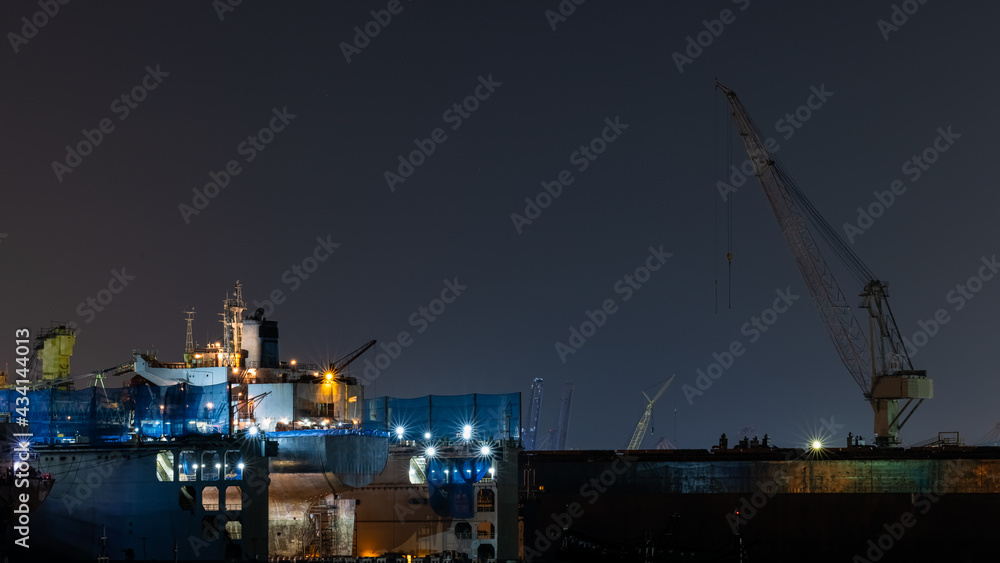 Container oil ship repair in shipyard at night. Can use for shipping or transportation