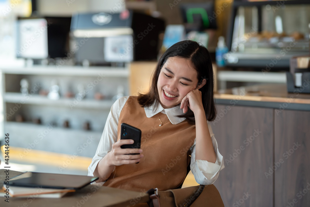 Image of an Asian woman happy using smartphone at a café. Image of an Asian woman happy using smartphone at a café.