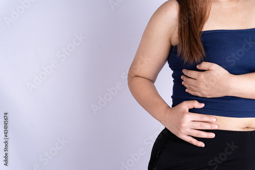 Woman hand touching waist or liver position isolated grey background.