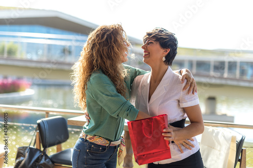 Two happy women. One of them receives a gift from the other.