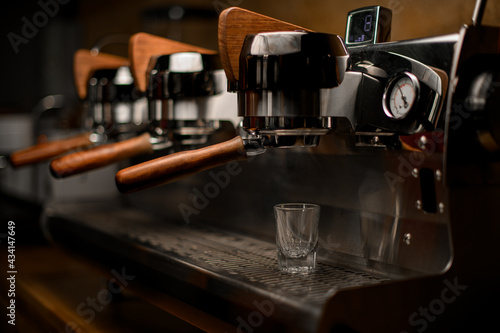 empty glass on steel surface of professional coffee machine in coffee shop