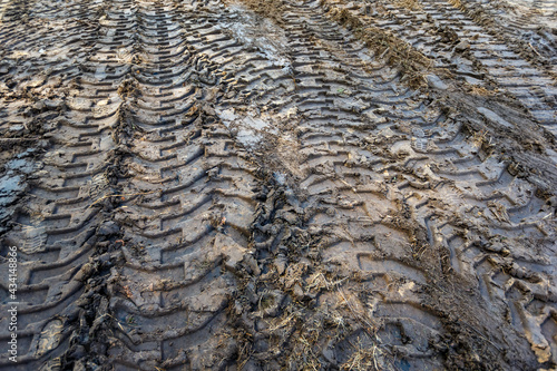 tractor tire tread marks on wet clay ground as pattern texture photo