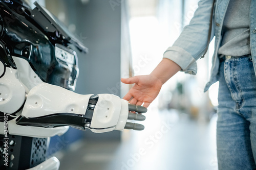Young woman shaking a modern robot hand