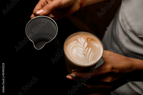 view of coffee drink with figure pattern on foam in glass in woman s hand
