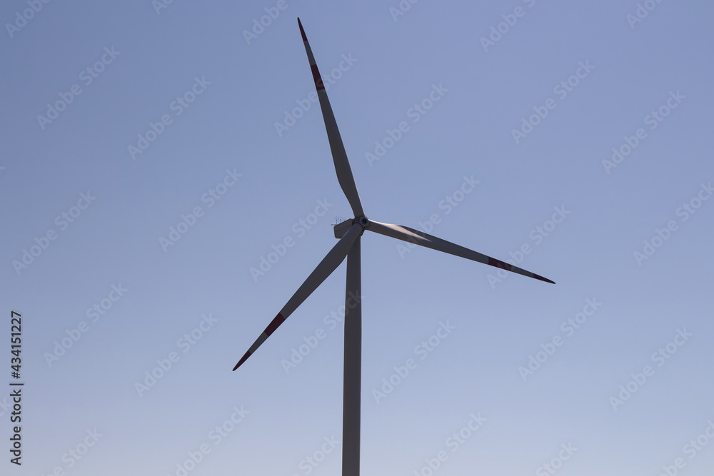 Close up view of windmill in Sigacik / Seferihisar district of Izmir / Turkey. Wind power turbine for clean, renewable energy. Sustainability concept. It is a sunny summer day.