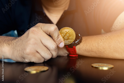 golden bitcoin in a businessman hand on table with soft focus and backlighting. cryptocurrency concept