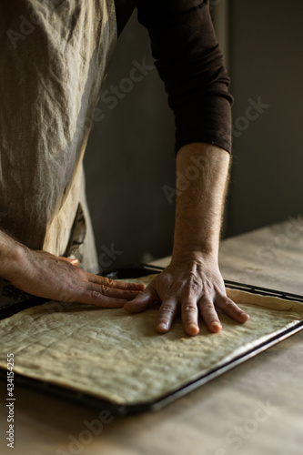 Billede på lærred Male hands spreading the dough on a baking sheet
