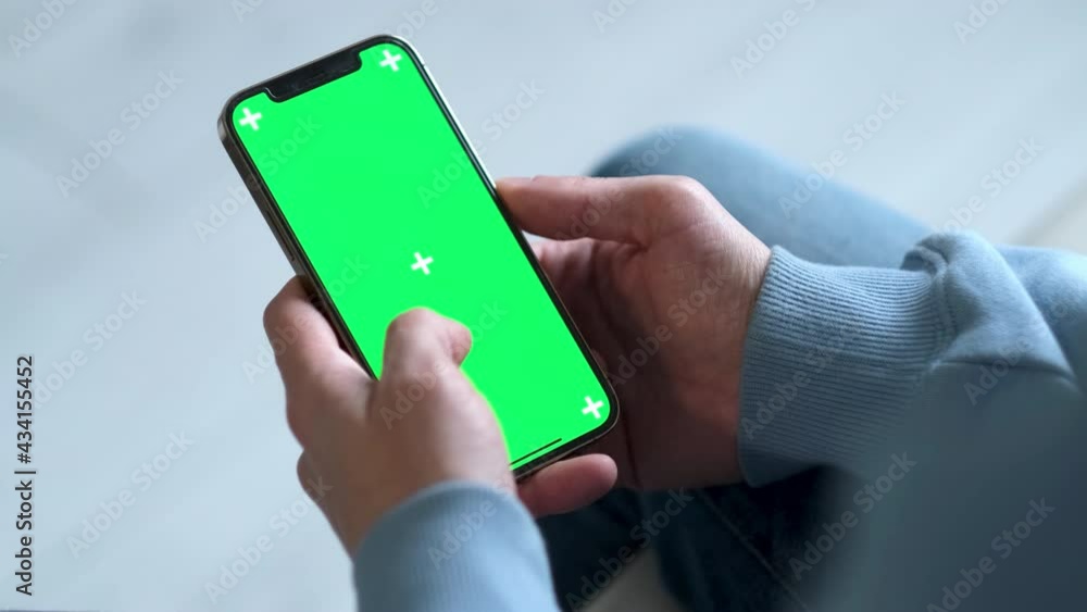 4k. man using iPhone 12 smartphone viewing green screen on phone press browsing chroma key online typing text reading social media close up hands 24.04.21 St.Petersburg Russia.